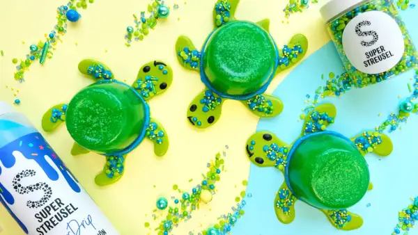 Drei grüne Wackelpudding-Schildkröten mit Streuseln und einem Drip-Fläschchen. Lustige Wackelpudding-Ideen für den Sommer.