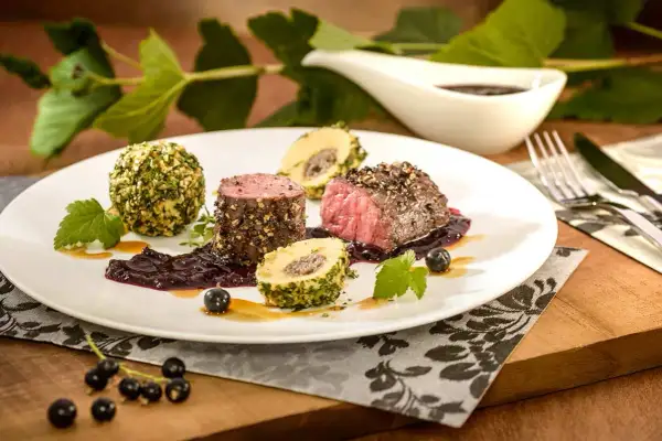 Edles Fleisch mit Kräuterkugeln und einer dunklen Sauce, inspiriert von schwarzen johannisbeere rezepten.