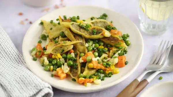 Gebratene Maultaschen mit Erbsen, Karotten und Mais, garniert mit Schnittlauch. Ein herzhaftes Gericht, das Lust auf mehr macht.