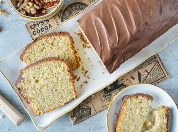 Saftiger Nusskuchen mit Schokoladenglasur, perfekt für Ihr nächstes nusskuchen rezept. Daneben liegen Walnüsse und ein Stück Kuchen.