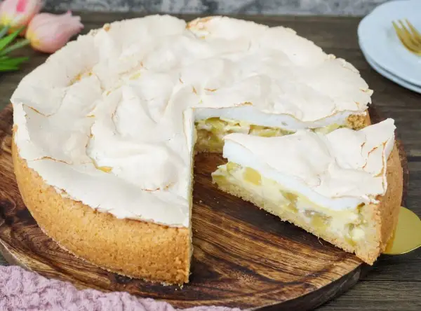 Ein saftiger Rhabarberkuchen mit Baiserhaube, ein Stück wurde bereits entnommen.