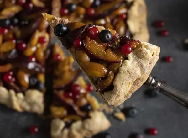 Ein Stück fruchtige Galette mit Pflaumen und Beeren, perfekt für ein einfaches Galette Rezept.
