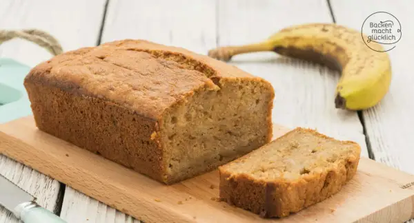 Saftiges Bananenbrot mit Dinkelmehl, frisch gebacken und auf einem Holzbrett angerichtet. Eine Scheibe ist bereits abgeschnitten.