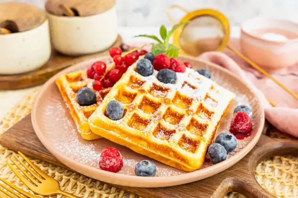 Goldene protein waffeln rezept mit frischen Beeren und Puderzucker bestäubt. Ein köstlicher Start in den Tag!